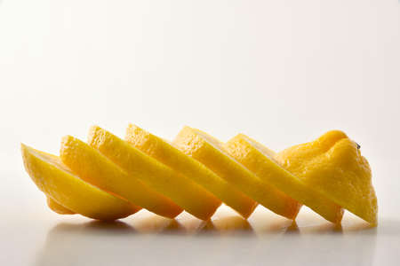 Detail of lemon cut into slices on a white table and white isolated background. Front view. Horizontal composition.の写真素材