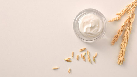 Oat body and facial moisturizer cream in glass jar with spikes on white table. Top view. Horizontal composition.の写真素材