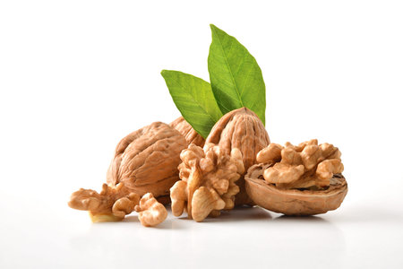 Walnuts in shell and broken showing seeds with leaves on white table and white isolated background....