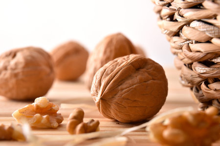 Macro detail of walnuts on wooden table with and pieces of fruit next to a wicker basket. Front...