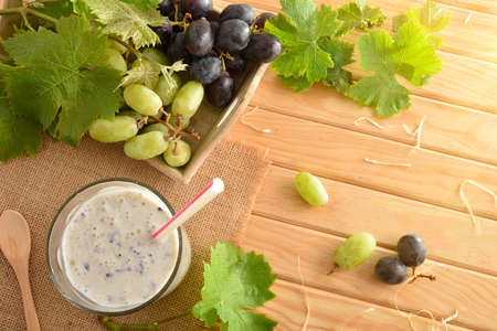 Organic grape drink and tray with bunches of white and red grapes on wooden table. Top view.の写真素材