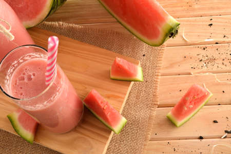 Natural watermelon juice with milk on a wooden table with cut fruit close up. Top view.の写真素材