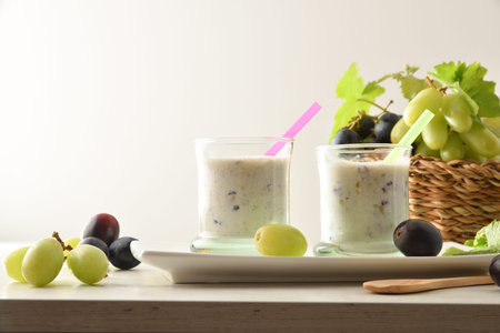 Organic grape drink on white plate with bunches of white and red grapes in basket on wooden table isolated background. Front view.の写真素材