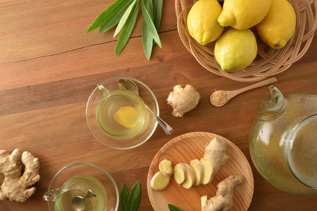 Ginger root with sliced portions and leaves on white table. Top view.