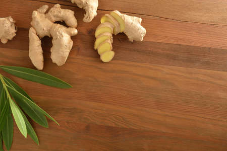 Ginger root with sliced portions and leaves on white table. Top view.の写真素材