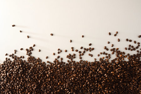 Pile of naturally dried coffee beans on one side on white table down. Top view. Horizontal...