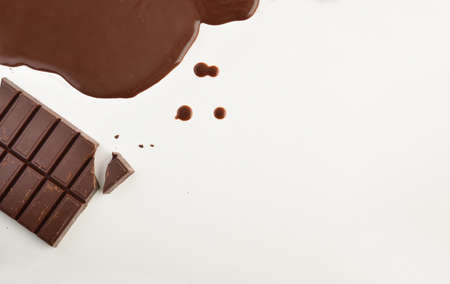 Background with pastry chocolate in tablet and melted on a white table. Top view. Horizontal composiiton.の写真素材