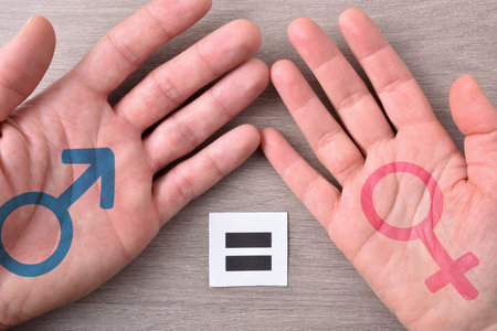 Man and woman hand with gender symbols and placard with equality symbol on wood table top view.