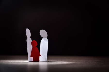 Concept of sexual abuse to underage girls with paper cutouts and dark background on wooden tableの写真素材