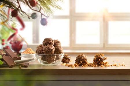 Chocolate balls with almond chips on table decorated for Christmas and window in the background. Front view. Horizontal composition.の写真素材