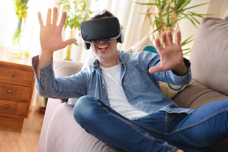 Man using virtual reality glasses lying on a sofa in the living room at home