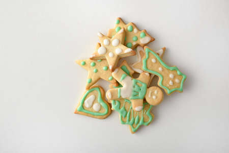 Assortment of Christmas shaped cookies decorated with white and green icing in a pile on white table. Top view. Horizontal composition.の写真素材