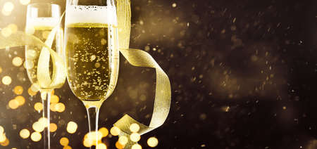 Event celebration concept with glasses of sparkling white, ribbon and golden bokeh. Front view.の写真素材