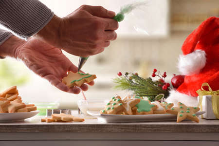 Decorating Christmas-themed cookies with colored icing on kitchen table with utensils. Top view. Horizontal composition.の写真素材