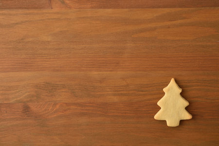 Christmas background with fir-shaped cookie in one corner on wooden background. Top view. Horizontal...