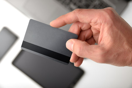 Electronic payment concept with hand showing credit card with mobile devices in the background. Top view.の写真素材