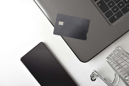 Online purchases concept with shopping cart credit card and devices on white table. Top view. Horizontal composition.の写真素材