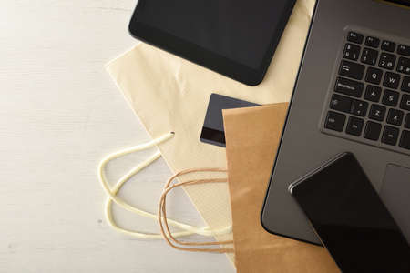 Online shopping concept with bank card and electronic devices on white wooden table with shopping bag. Top view.の写真素材