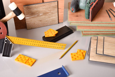 laminated flooring and assorted tools for placement on a gray table. Elevated view. Horizontal...