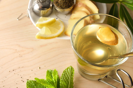 Cup of green tea with ginger lemon and mint on wooden table with leaves on wooden table detail....
