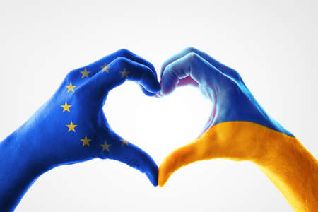 Concept of support from the European Union to Ukraine with painted hands of each flag forming a heart on white backgroundの写真素材