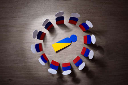 Concept Russian invasion in Ukraine with cutouts of Russian men surrounding Ukrainian cutout lying on the groundの写真素材