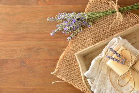 Natural lavender soap bar on towel in wooden tray on wooden table with bouquet of lavender flower spikes. Topview. Landscape composition.の写真素材