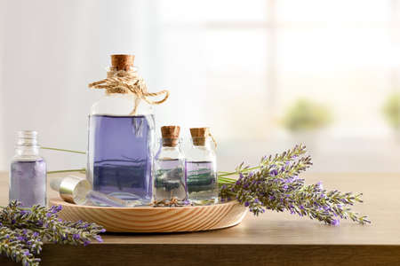 Glass containers with essence of lavender with bouquets of spikes around on wood in a room. Frontview. Landscape composition.の写真素材