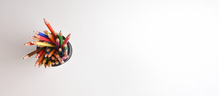 Background with group of colored pencils of various colors in a penholder on a white. Top view....