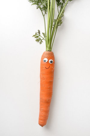Fresh carrot with face on white isolated background. Vegetables child healthy eating conceptの写真素材