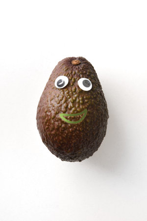 Fresh avocado with face on white isolated background. Fruit and vegetables child healthy eating conceptの写真素材