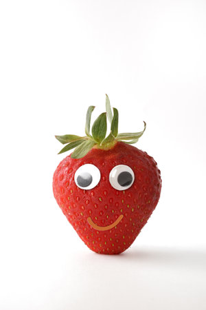 Healthy strawberry with face on white isolated background. Fruits and vegetables child healthy eating conceptの写真素材