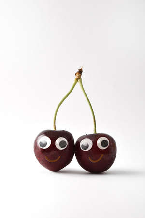 Healthy fresh cherries with face on white isolated background. Fruits and vegetables child healthy eating conceptの写真素材