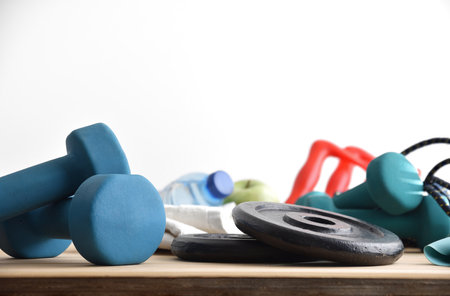 Background of sports equipment and home healthy living on a wooden floor with dumbbells, weights, elastic bands for healthy life with white isolated background. Front view.の写真素材