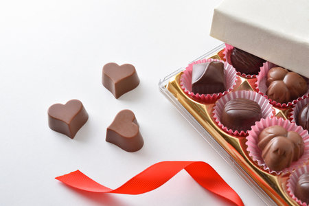 Box with assortment of chocolates on white table for event with red bow. Top elevated view.の写真素材