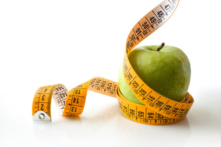 Apple rolled by a tape measure reflected on white base and white isolated background. Healthy lifestyle. Front view.の写真素材