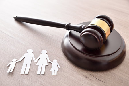 Family and minor judicial protection concept with gavel and family cutout on wooden table. elevated viewの写真素材