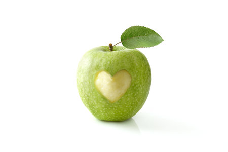 Green apple eaten in the center with a heart shape reflected on white table and isolated background. Front view.の写真素材