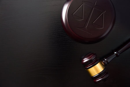 Background with symbolic objects of justice such as gavel and balance on black wooden table. top viewの写真素材