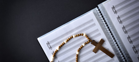 Music and religious choir with folder with sheet music and wooden cross on top on black table. top view.の写真素材