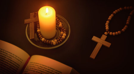 Christian spiritual environment for praying with candle illuminating the symbol of the cross and bible on black table at night. Top elevated view.の写真素材