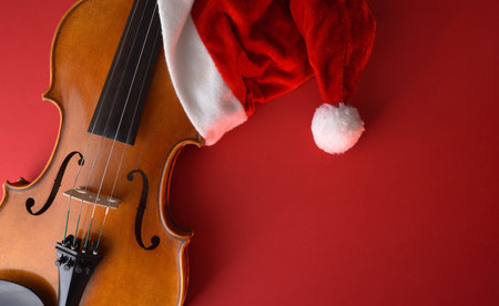 Detail of violin body with Santa hat on the left on a red background. Top view.の写真素材