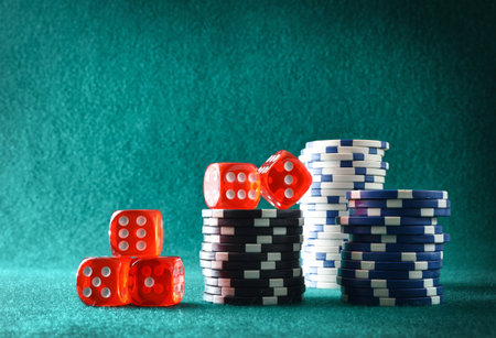 Casino dice game background with pile of betting chips on green felt mat and green isolated mat background. Front view.の写真素材