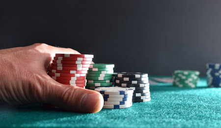 Background with hand betting game chips on green mat and isolated dark background. Front view.の写真素材