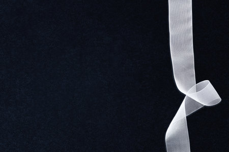 White tulle ribbon with waves on right side on textured isolated dark background. Top view.の写真素材