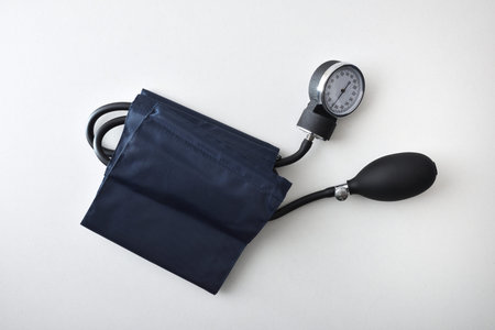 Manual blood pressure monitor with blue cuff isolated on white table. Top view.