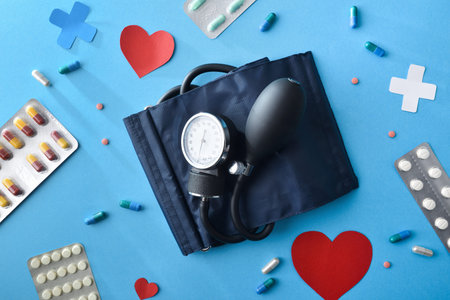 Concept of blood pressure treatment with blood pressure monitor and medications on blue background. Top view.の写真素材