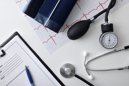 Heart health and blood pressure check with measuring tools on white doctor table with folder and...