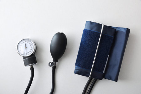 Detail of manual blood pressure monitor with blue cuff isolated on white table. Top view.