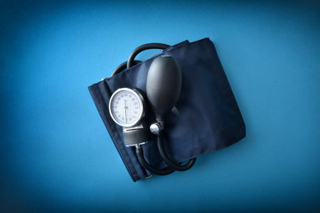 Detail of manual blood pressure monitor with blue cuff isolated on blue. Top view.